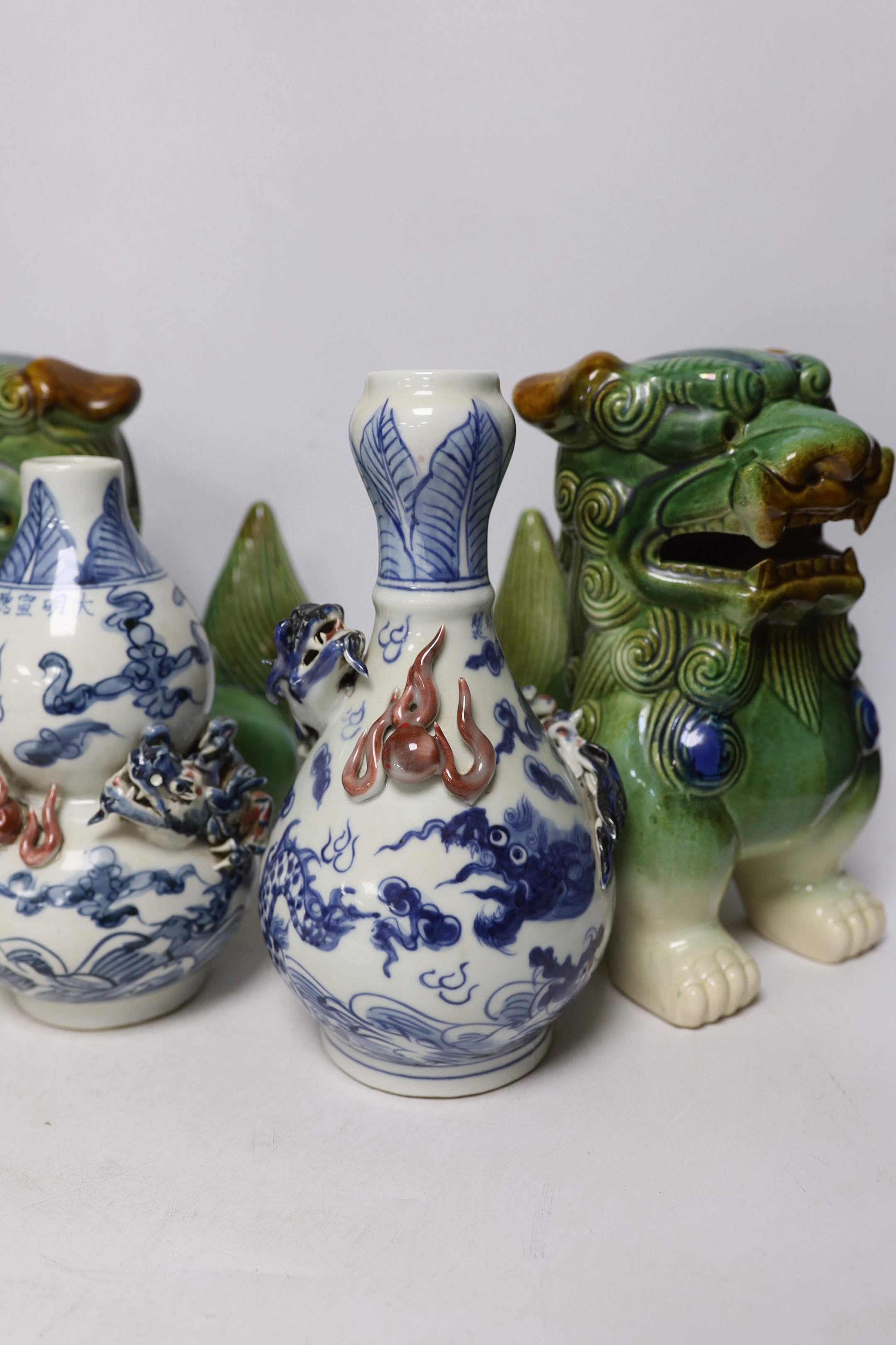 Two Chinese blue and white with iron red ‘dragon’ vases and a near pair of lion dogs, tallest 26cm
